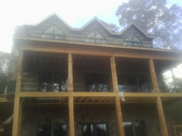 Dormers and porch framing on a large log home under construction — Roof Coating work by our crew in Gaylord