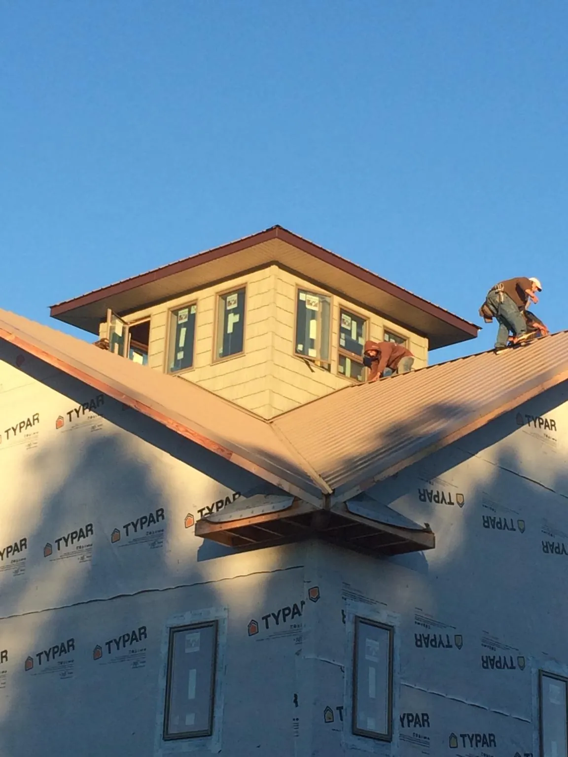 Roofers working around a rooftop cupola on a new metal roof at sunset — Roof Waterproofing in Gaylord by Roofing Brothers